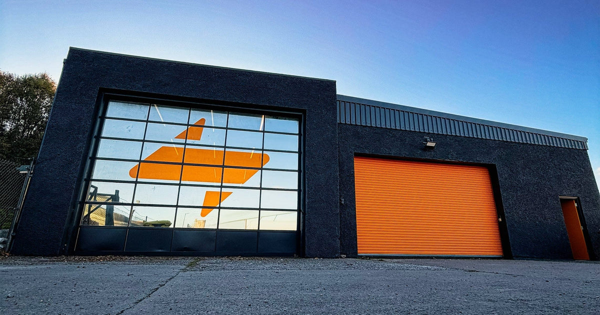 Modern Stoltman Strength Centre building with large glass door featuring a Stoltman logo and orange garage door.