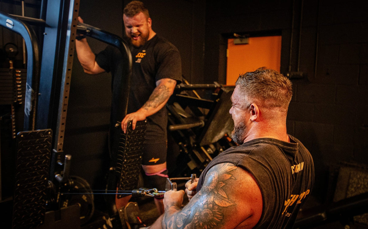 Two worlds strongest brothers working out with weightlifting equipment in the gym.